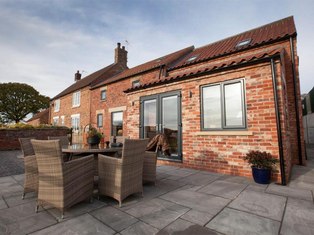 a patio with a table and chairs in front of a brick house at Deerholme Cottage in Malton