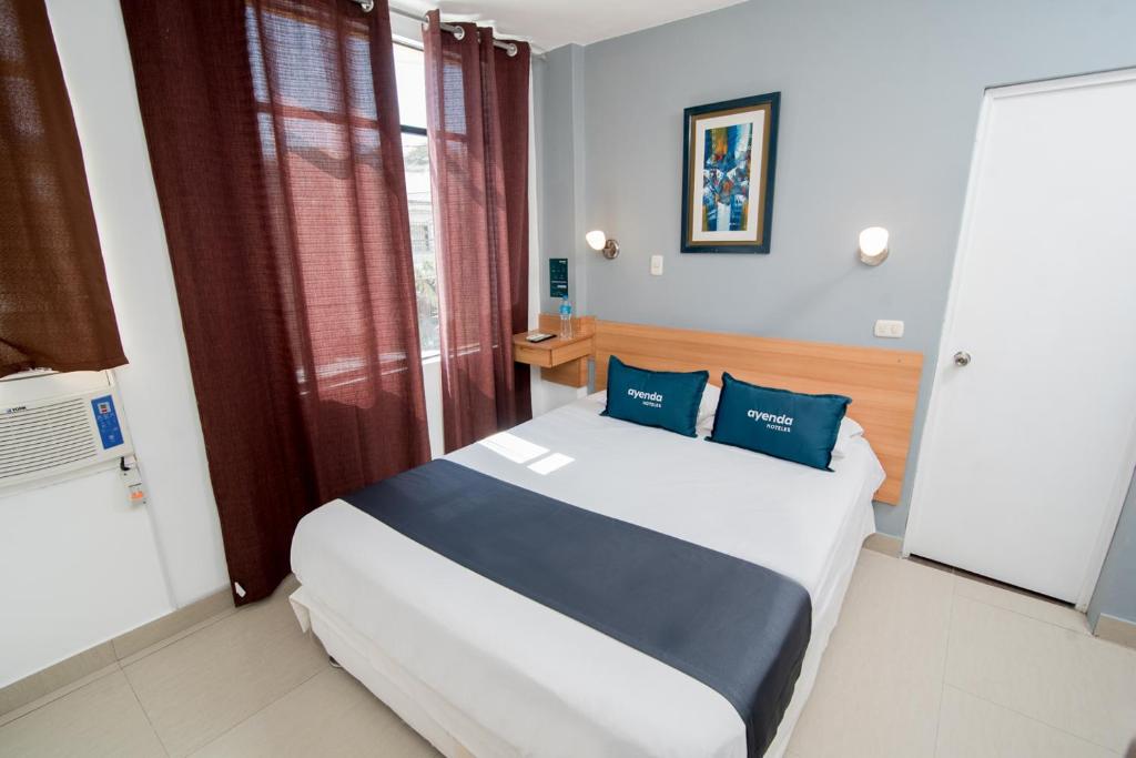 een slaapkamer met een groot bed met blauwe kussens bij Ayenda Apart La Hacienda in Piura