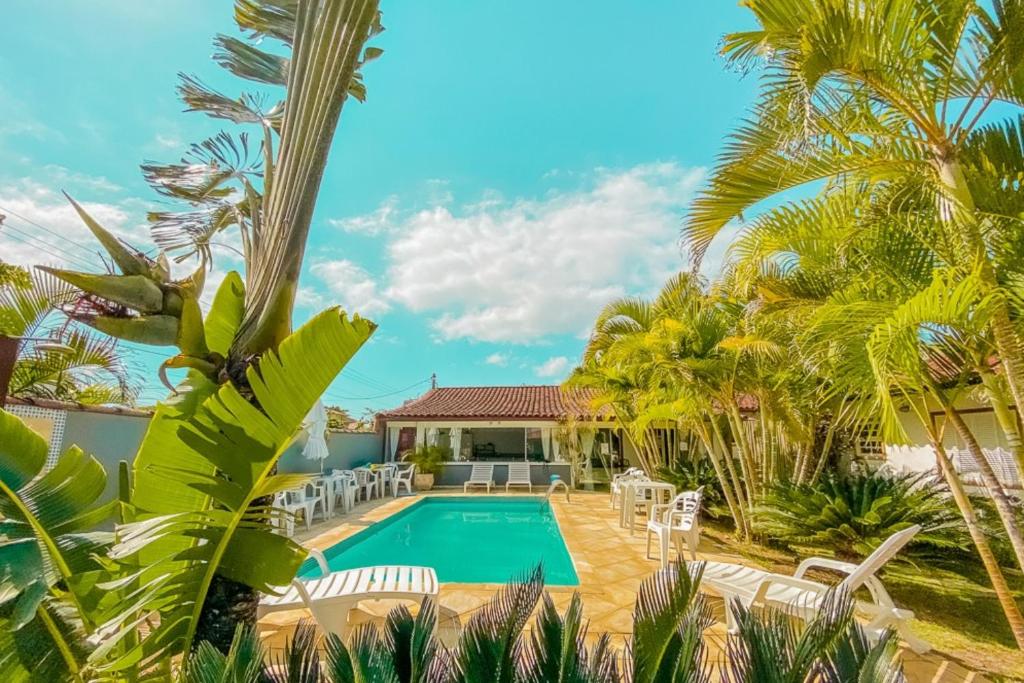 a villa with a swimming pool and palm trees at Pousada Jardim de Búzios in Búzios