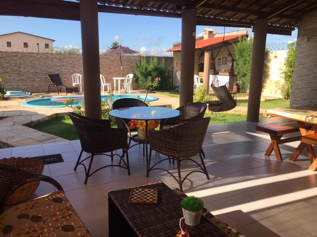 eine Terrasse mit Stühlen, einem Tisch und einem Pool in der Unterkunft Taíba Downwind House in São Gonçalo do Amarante