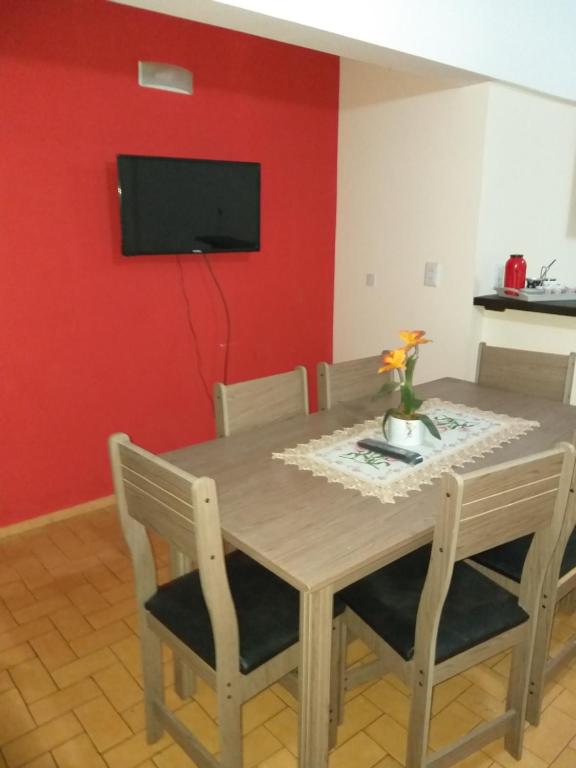 ein Esszimmer mit einem Tisch und einem TV an einer roten Wand in der Unterkunft Departamento 3A in Puerto Iguazú