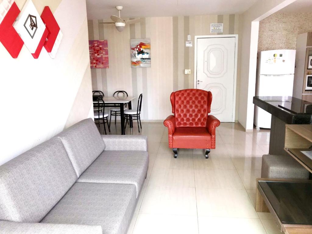 sala de estar con sofá y silla roja en INCRÍVEL Ap a 100m do MAR com Ar e Wi-Fi, en Balneário Camboriú