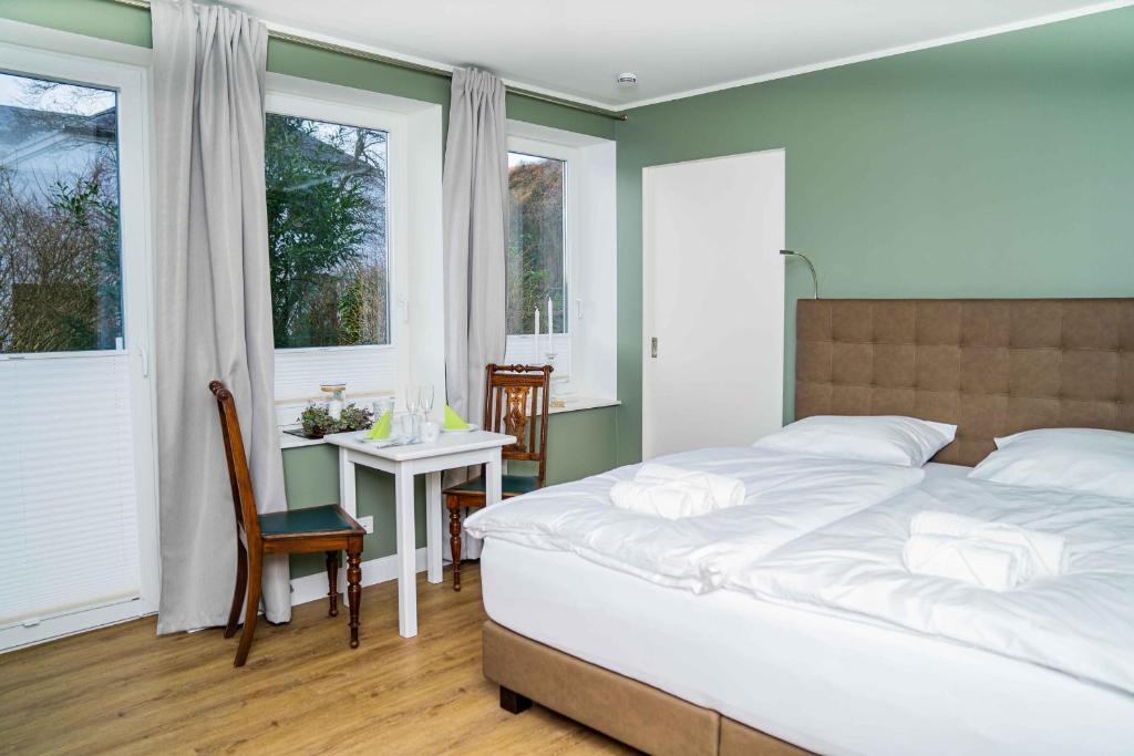 a bedroom with a bed and a table and windows at Gästehaus "Alte Bücherei" Satrup in Mittelangeln