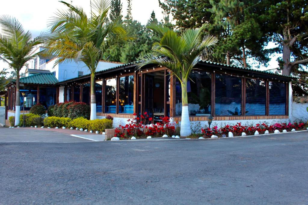 GachancipáにあるHotel Las Palmeras Gachancipaの駐車場内のヤシの木と花の建物
