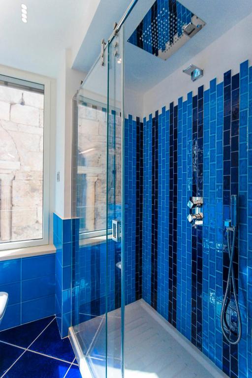 a blue tiled bathroom with a glass shower at La Suite Del Cavaliere in Amalfi