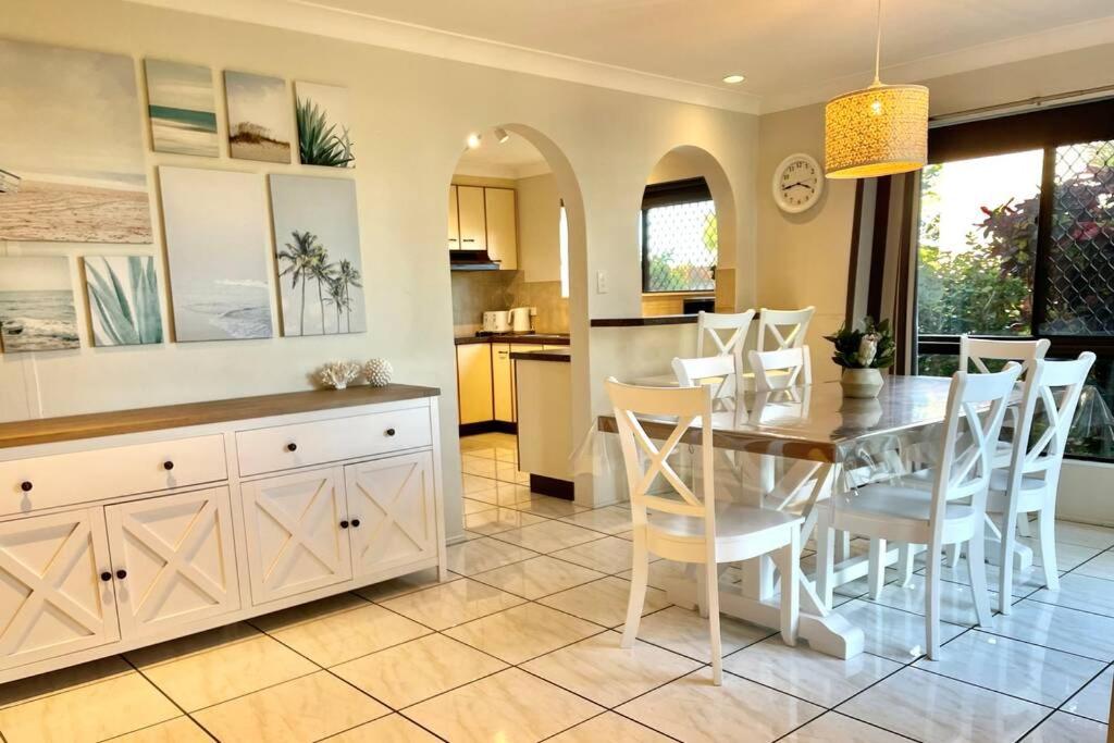 a kitchen and dining room with a table and chairs at WHISPERING PALMS in Bongaree