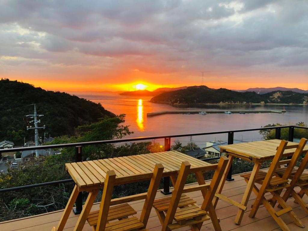 einen Tisch und Stühle auf einem Balkon mit Blick auf den Sonnenuntergang in der Unterkunft MY LODGE Naoshima in Naoshima