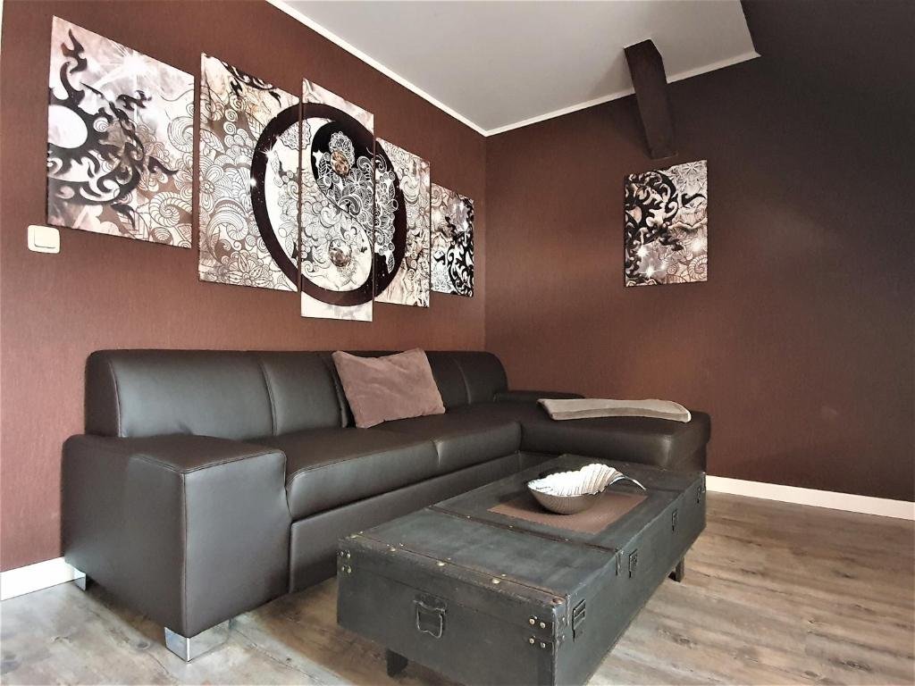 a living room with a leather couch and paintings at Ferienwohnung Summer in Karlshagen