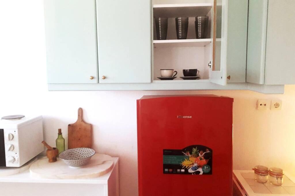 una nevera roja en una cocina con armarios blancos en Summer aura - seaside place, en Istron