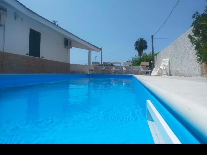 - une piscine d'eau bleue dans une maison dans l'établissement Villa delle Muse, à Fontane Bianche