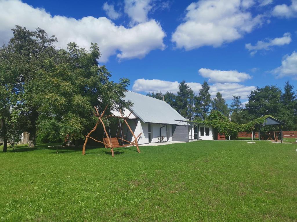 eine weiße Scheune mit einem Baum auf dem Feld in der Unterkunft Agrochalupki in Korczowe