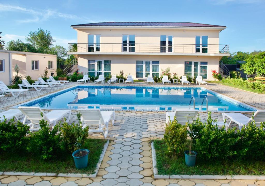 a villa with a swimming pool in front of a house at Family Resort Bambora in Gudauta