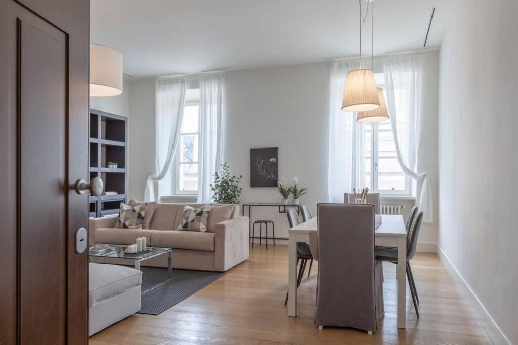 een woonkamer met een bank en een eettafel bij Palazzo Tergesteo Tirabora Suite Apartments in Trieste