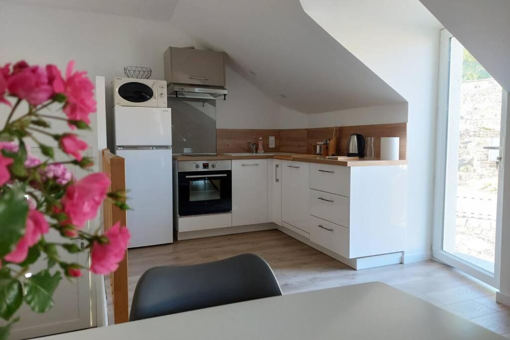 une cuisine avec des appareils blancs et une table avec des fleurs roses dans l'établissement Gîte au cœur des Combrailles, à Saint-Georges-de-Mons