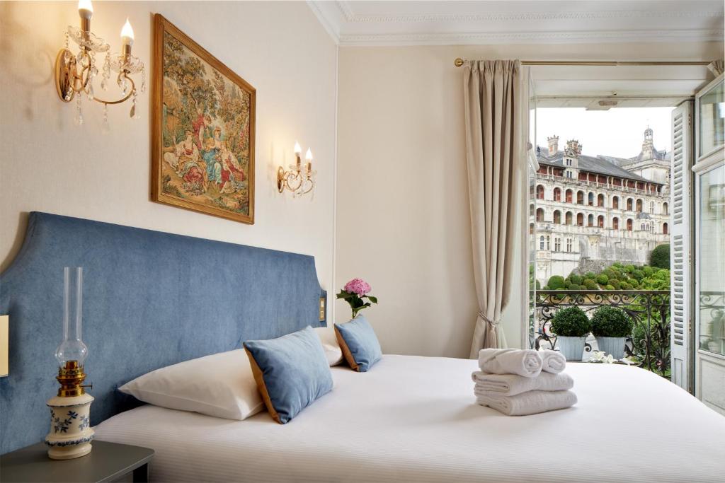 a bedroom with a bed with a blue headboard and a window at Hôtel De France Et De Guise - 1891 in Blois