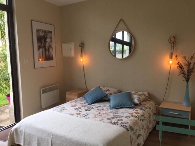 1 dormitorio con cama y espejo en la pared en Chambre dans dépendance Maison de Ville + abri vélos, en Saumur