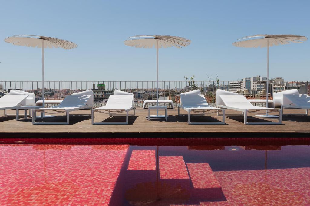 a pool with white chairs and umbrellas on a rooftop at Lumen Hotel & The Lisbon Light Show in Lisbon