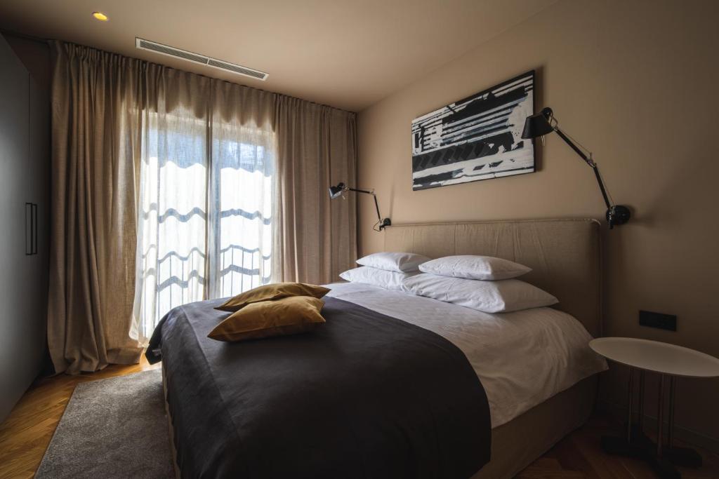 a bedroom with a bed with white pillows and a window at DESIGN hotel VERBENICUM in Vrbnik