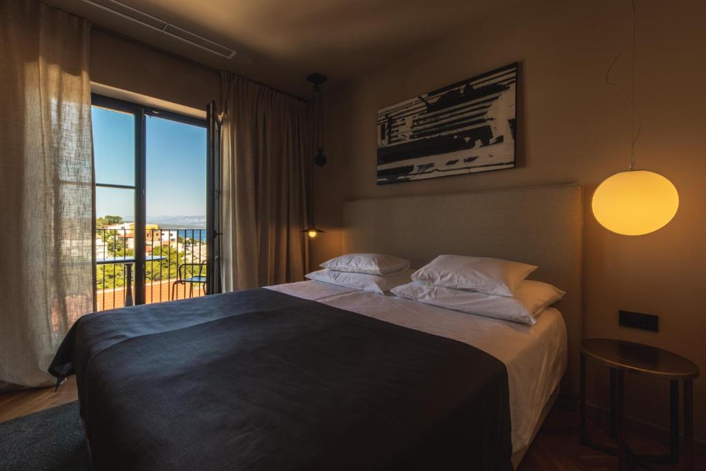 um quarto com uma cama e uma grande janela em DESIGN hotel VERBENICUM em Vrbnik