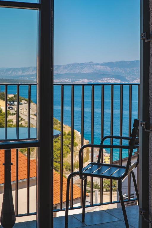 a chair on a balcony looking out at the ocean at DESIGN hotel VERBENICUM in Vrbnik