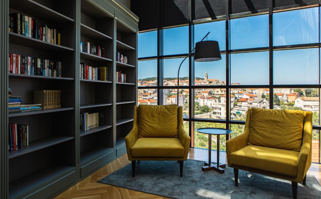 two chairs in a library with bookshelves at DESIGN hotel VERBENICUM in Vrbnik