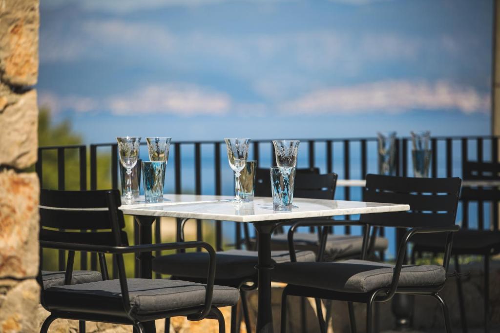 a table with chairs and glasses on a balcony at DESIGN hotel VERBENICUM in Vrbnik