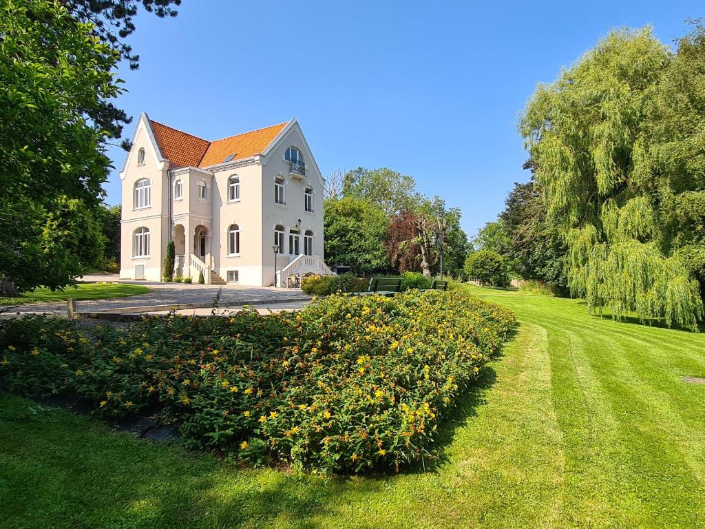 una gran casa blanca con un patio con flores en Le Domaine de La Gontherie Gîte de groupe, en Réty