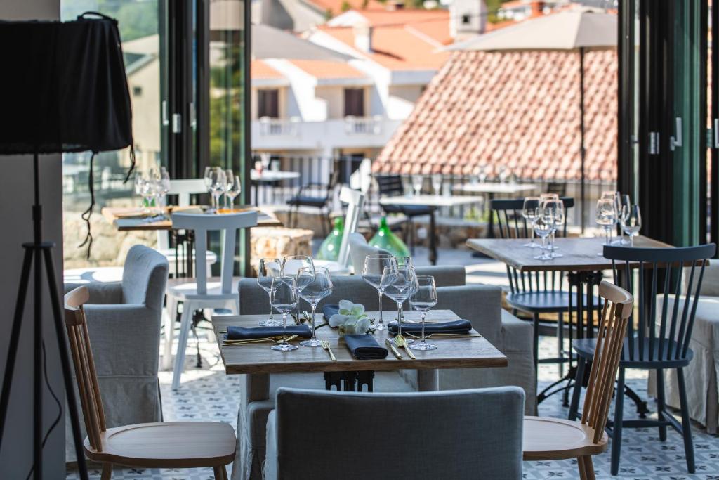 a restaurant with tables and chairs with wine glasses at DESIGN hotel VERBENICUM in Vrbnik