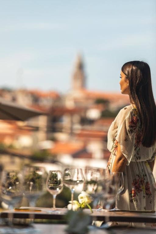 a woman standing in front of a table with wine glasses at DESIGN hotel VERBENICUM in Vrbnik