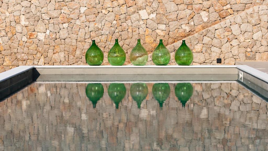 a row of green glass vases sitting on a wall at DESIGN hotel VERBENICUM in Vrbnik