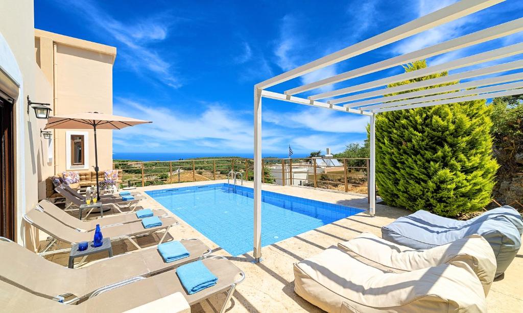 a villa with a swimming pool and patio furniture at Cretan Sunny Villa Heated Pool in Kournás