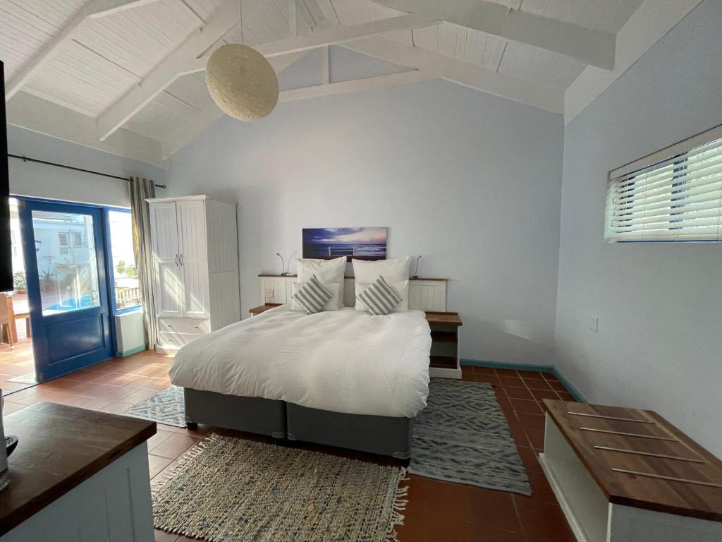 a white bedroom with a bed and a table at BlueSky Arniston Guest House in Arniston