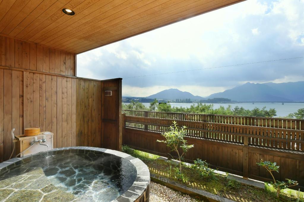 a hot tub on a deck with a view of the water at Hotel Koryu in Fujikawaguchiko