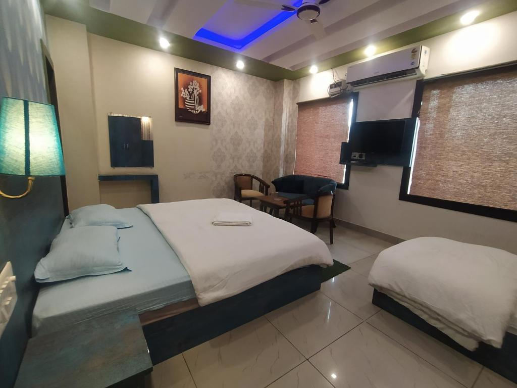 a bedroom with two beds and a table and a chair at Hotel Geeta Residency Haridwar in Haridwār