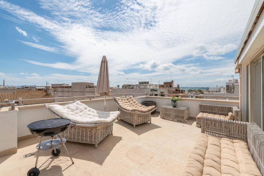 - un balcon avec des chaises en osier et un parasol dans l'établissement Casa REWA, à Port d'Alcúdia