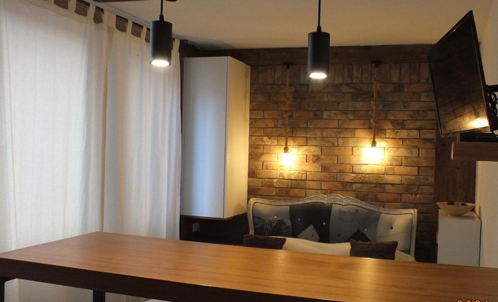a dining room with a table and a brick wall at Little L Apartments Dorćol in Belgrade