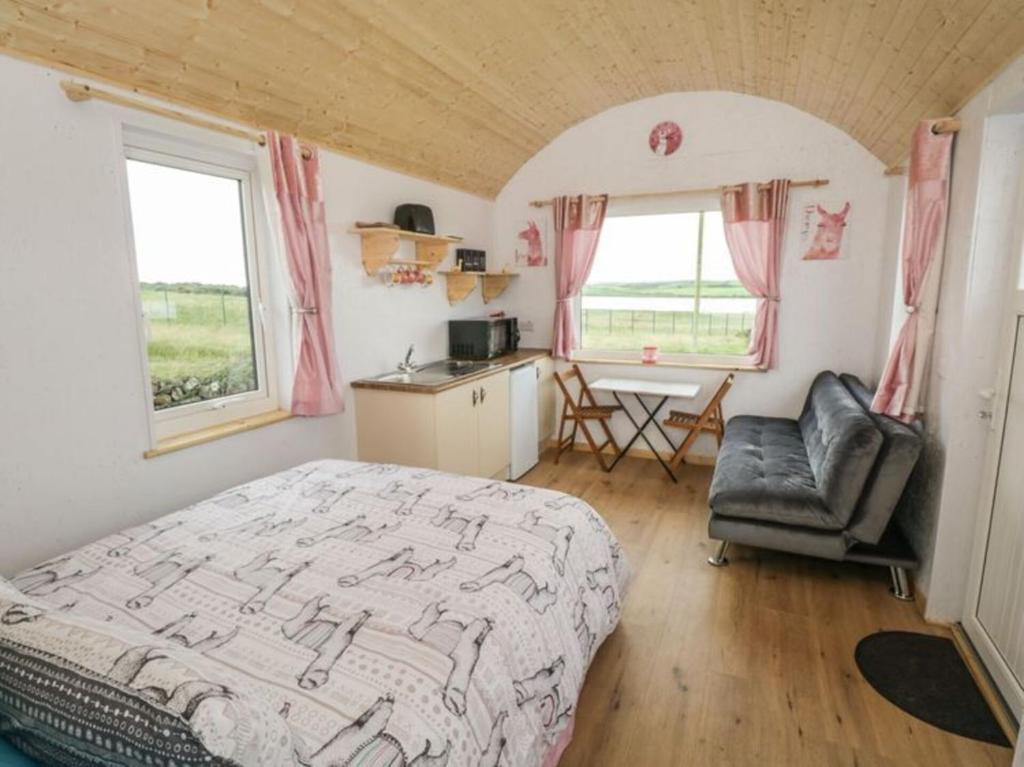 een slaapkamer met een bed, een stoel en een tafel bij The Beautiful Lazy Llama Shepherd Hut Farm Stay in Ballyshannon