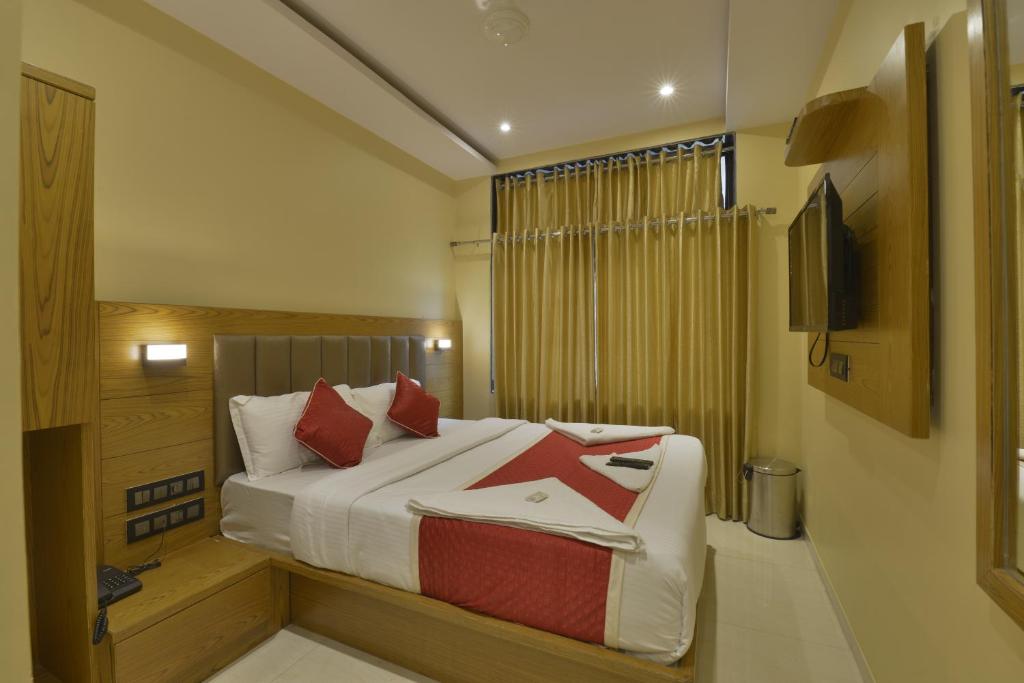 1 dormitorio con 1 cama con almohadas rojas y TV en Hotel Residency Park, en Bombay