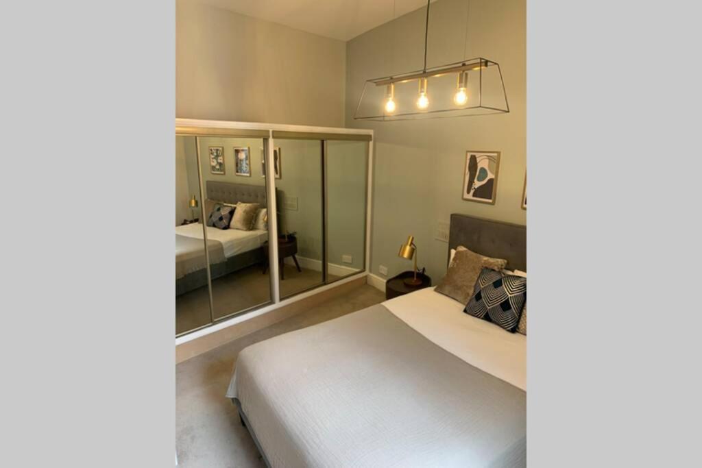 um quarto com uma grande cama branca e um espelho em Kensington Apartments em Londres