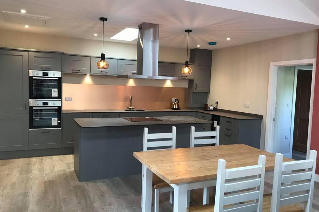 eine Küche mit einem Holztisch und weißen Stühlen in der Unterkunft Delightful detached Cottage in Village Centre in Plymtree