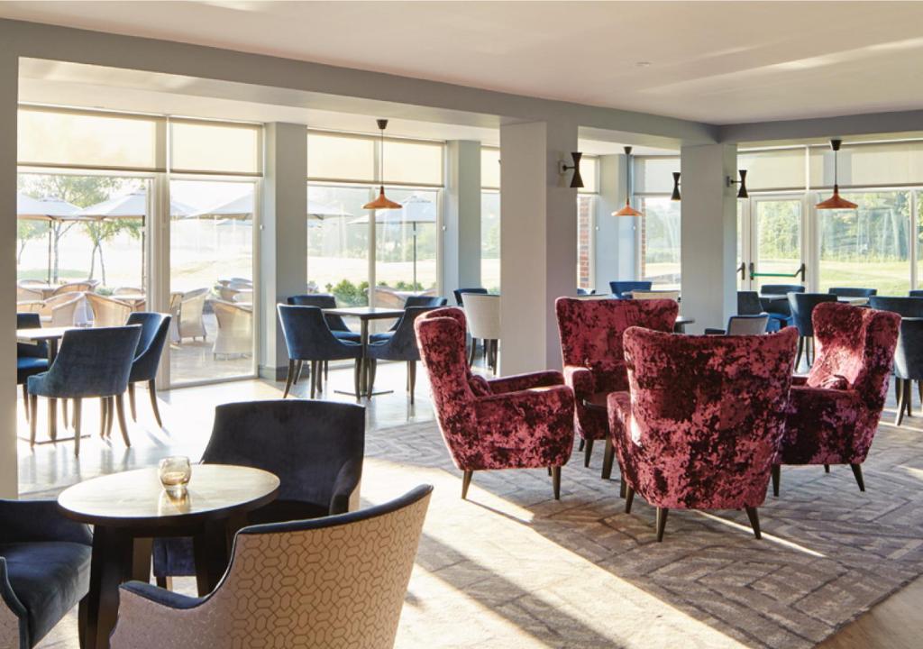 a restaurant with red chairs and tables and windows at Formby Hall Golf Resort & Spa in Southport