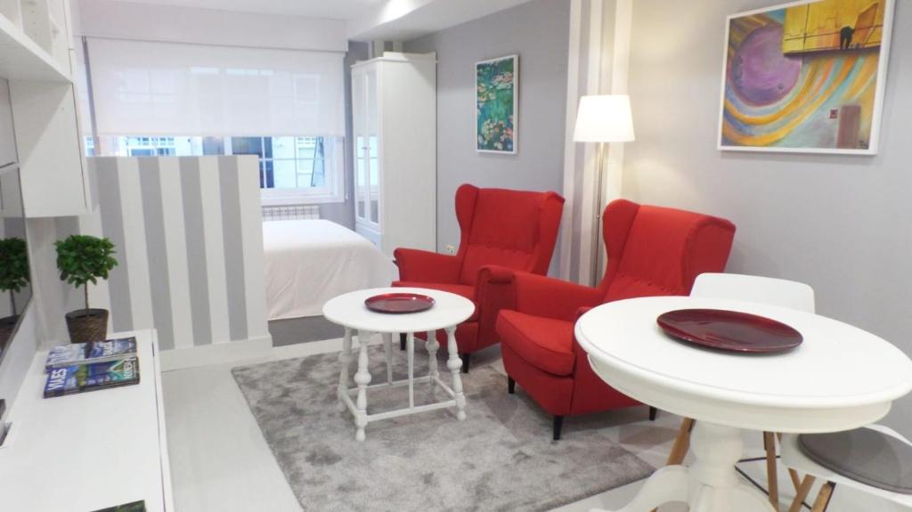 a room with red chairs and a table and a bed at ESTUDIO EN BAIONA- PLAYA SANTA MARTA in Baiona