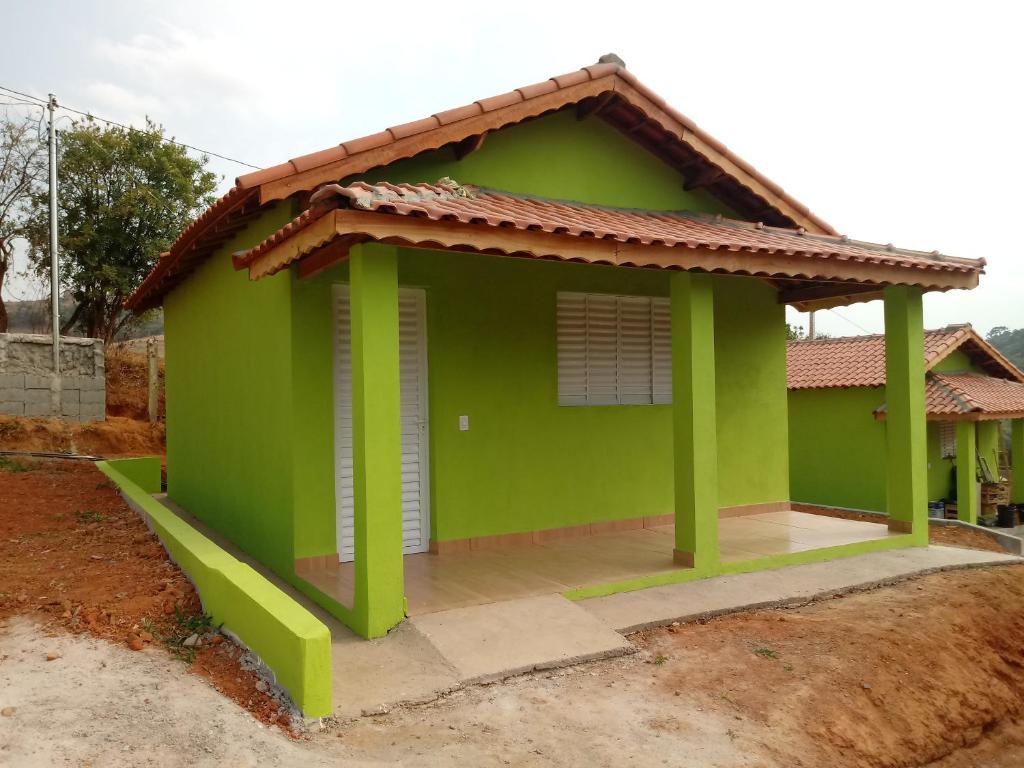una pequeña casa verde con techo rojo en Pousada Rota da Serra, en Munhoz