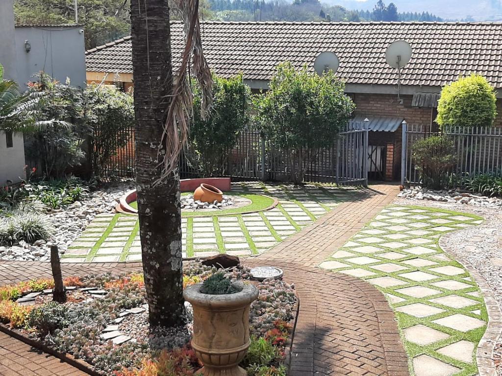 a garden with a tree and a brick walkway at Forest hills lodge in Louis Trichardt