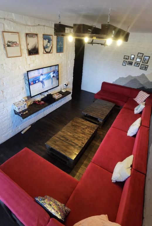 シェレゲシュにあるBear Holeのリビングルーム(赤いソファ、薄型テレビ付)