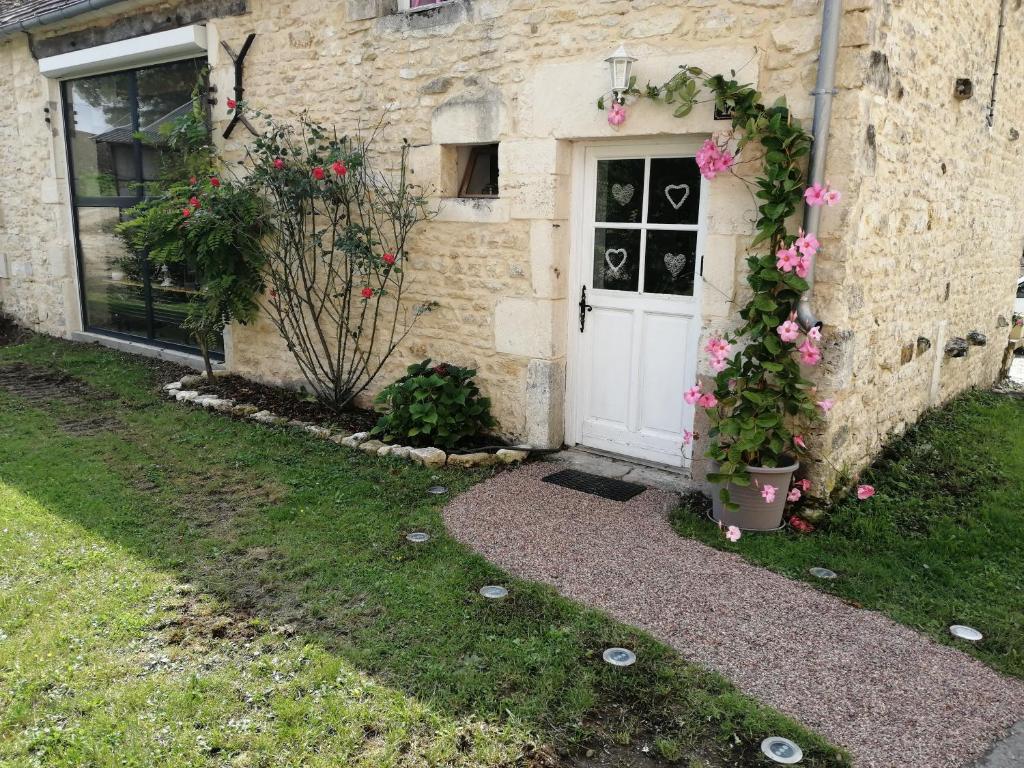 a brick house with a white door and pink flowers at Séjour à la campagne in Bouhy