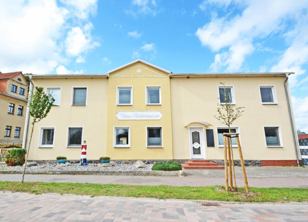 un grand bâtiment jaune avec un panneau devant lui dans l'établissement Ferienanlage Zempin Haus Achterwasser, à Zempin