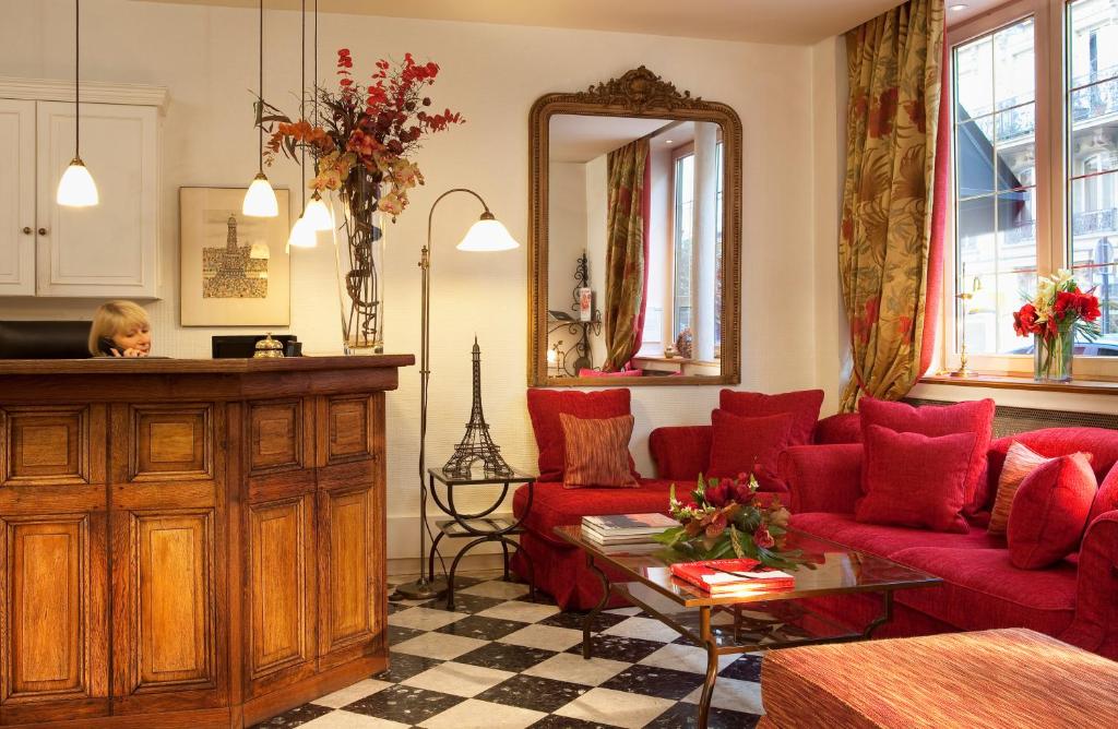 a woman in a living room with red couches and a mirror at New Orient Hotel in Paris