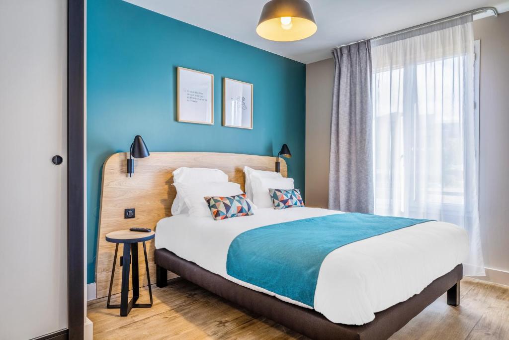 une chambre avec un grand lit et un mur bleu dans l'établissement Appart'City Confort St Quentin en Yvelines - Bois D'Arcy, à Bois-dʼArcy