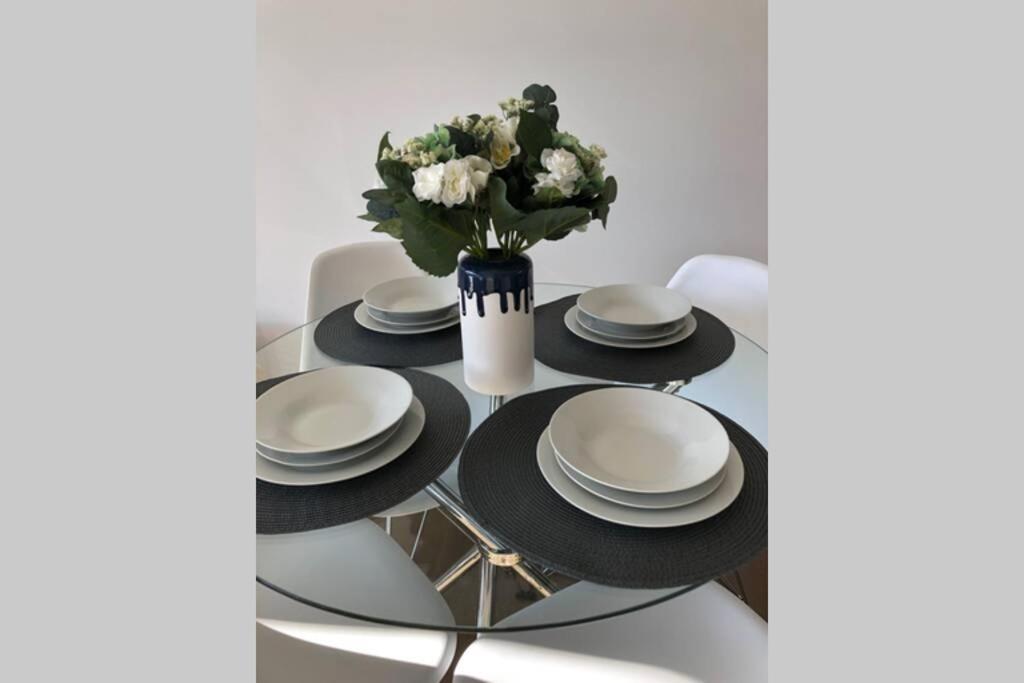 una mesa con platos blancos y negros y un jarrón con flores en Liverpool holiday apartment 2Bedroom 2Bathroom, en Liverpool